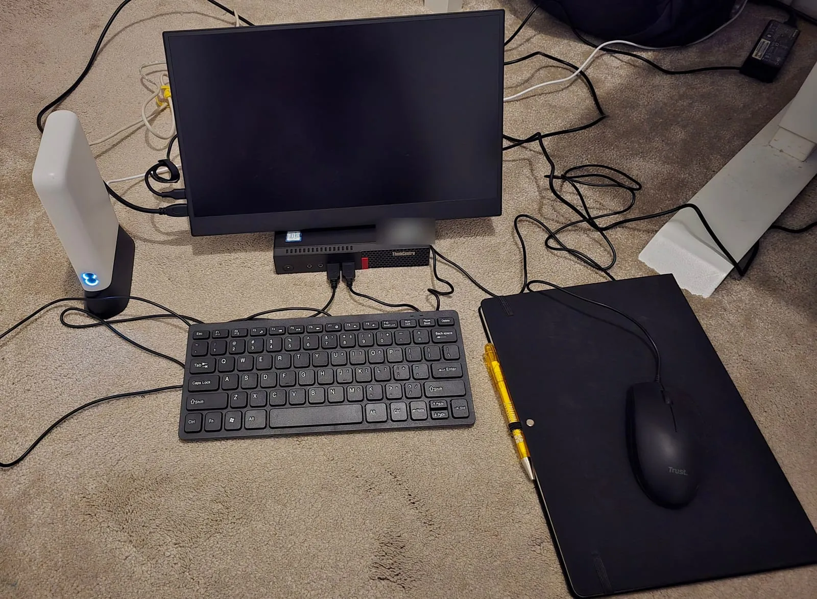The lab on the floor: a white EE 4G router, a Lenovo ThinkCentre Tiny under a portable monitor, a keyboard and a mouse